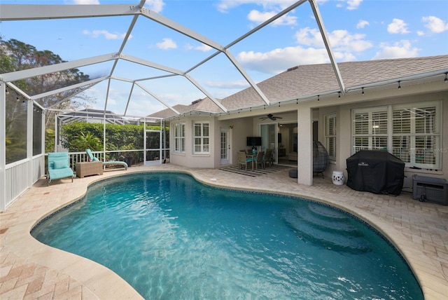 pool featuring glass enclosure, a patio, a ceiling fan, and grilling area