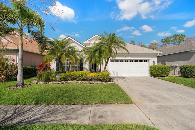 view of front facade with a front yard, a garage, driveway, and stucco siding