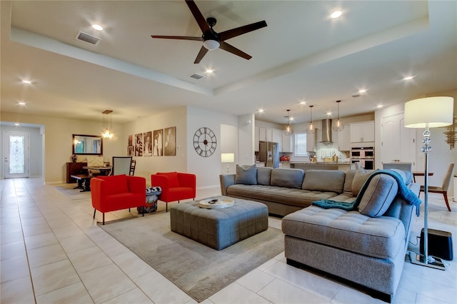 living room featuring light tile patterned floors, visible vents, and a raised ceiling