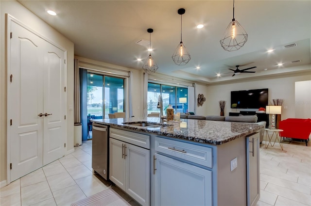 kitchen featuring visible vents, ceiling fan, an island with sink, dark stone countertops, and a sink