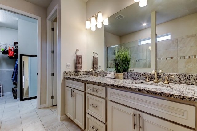 bathroom with double vanity, a spacious closet, a tile shower, and a sink