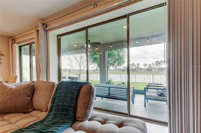 tiled living room with a ceiling fan and a water view