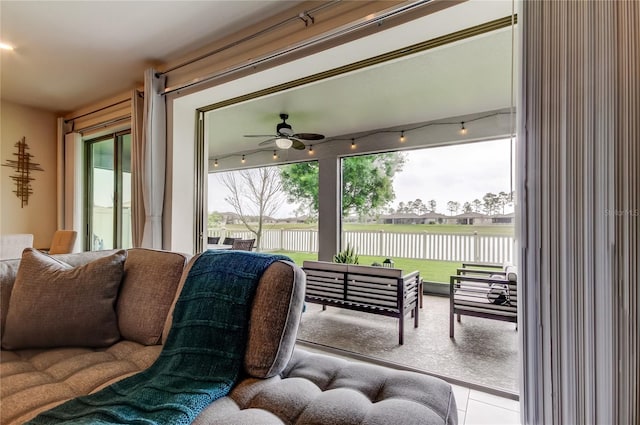 tiled living room featuring a water view, ceiling fan, and rail lighting