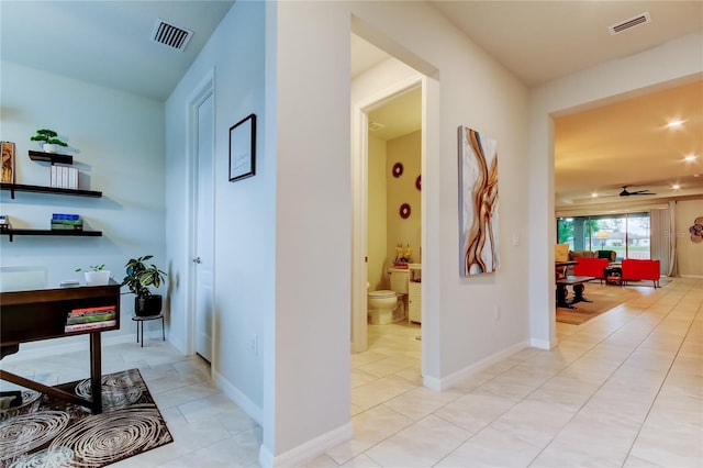 hallway with light tile patterned flooring, baseboards, and visible vents