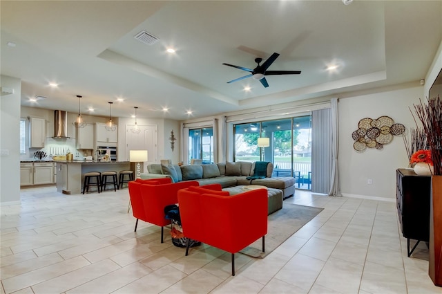 living area with visible vents, baseboards, ceiling fan, recessed lighting, and a raised ceiling