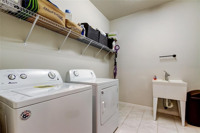 washroom featuring light tile patterned floors, baseboards, laundry area, and washing machine and clothes dryer