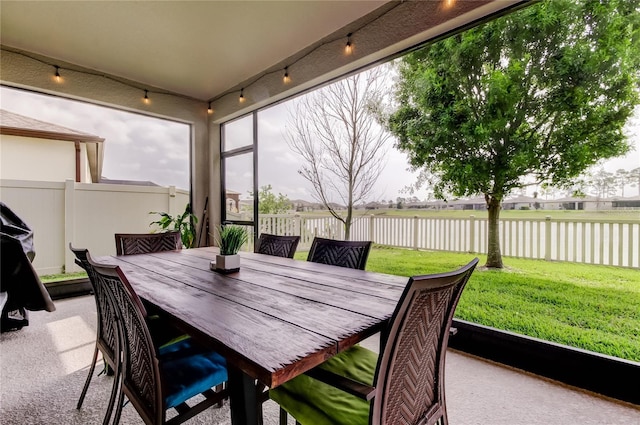 sunroom / solarium with track lighting and a water view