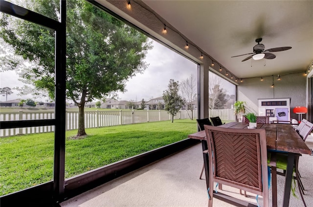 sunroom / solarium featuring rail lighting and a ceiling fan