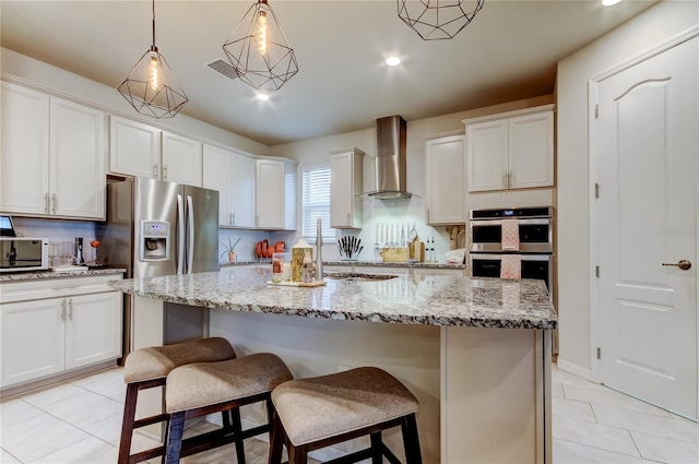 kitchen with stainless steel appliances, a breakfast bar area, wall chimney exhaust hood, light tile patterned flooring, and decorative backsplash