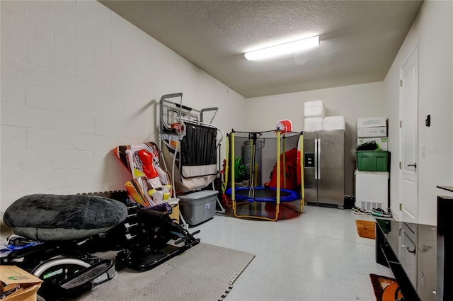 garage featuring concrete block wall, stainless steel fridge, and water heater