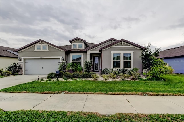 craftsman-style home featuring stucco siding, an attached garage, concrete driveway, and a front lawn