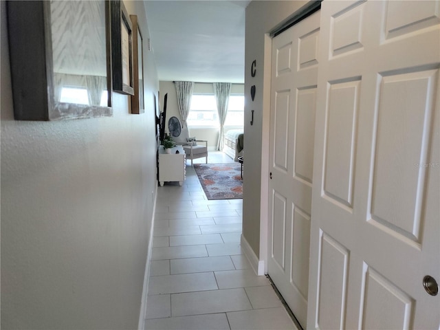 hallway featuring light tile patterned flooring and baseboards