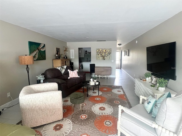 tiled living area with baseboards and a sink