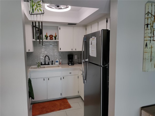 kitchen with open shelves, light countertops, freestanding refrigerator, white cabinetry, and a sink