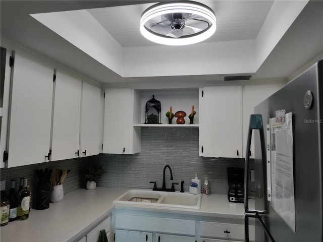 kitchen with open shelves, light countertops, freestanding refrigerator, white cabinets, and a sink