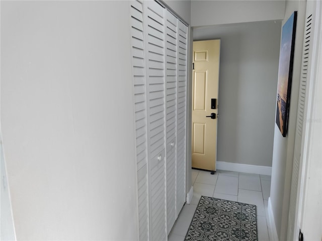 corridor featuring light tile patterned flooring and baseboards