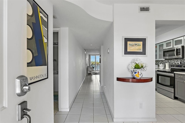 hallway featuring baseboards, visible vents, and light tile patterned flooring