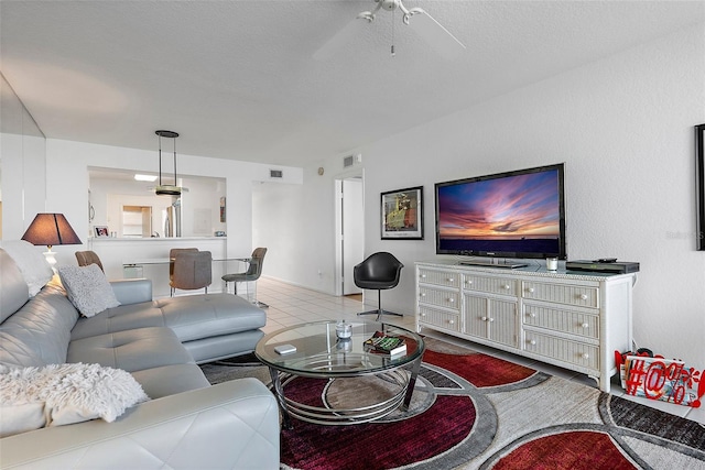 living area featuring a textured ceiling, ceiling fan, and light tile patterned flooring