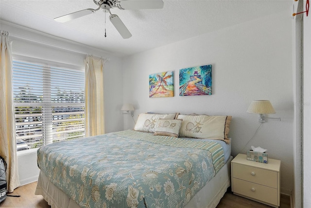 bedroom featuring a textured ceiling, a ceiling fan, and wood finished floors