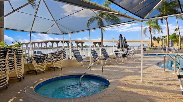 community pool with a community hot tub, a lanai, a patio area, and a water view