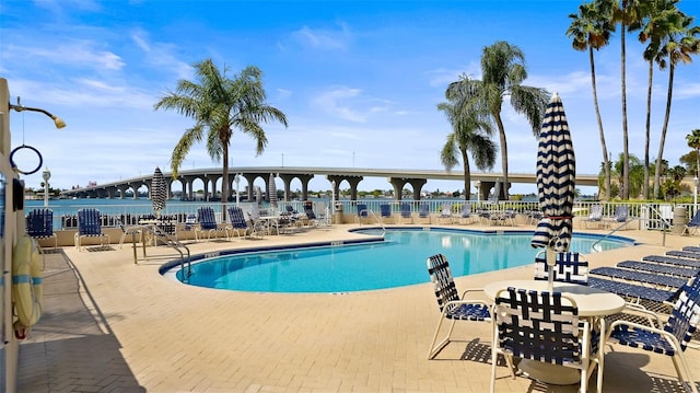 pool with a water view, a patio area, and fence