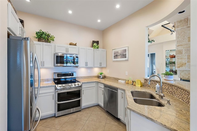 kitchen featuring light tile patterned floors, appliances with stainless steel finishes, a sink, and white cabinetry