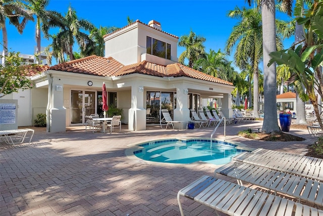 rear view of house featuring a patio area, a tile roof, a chimney, and stucco siding