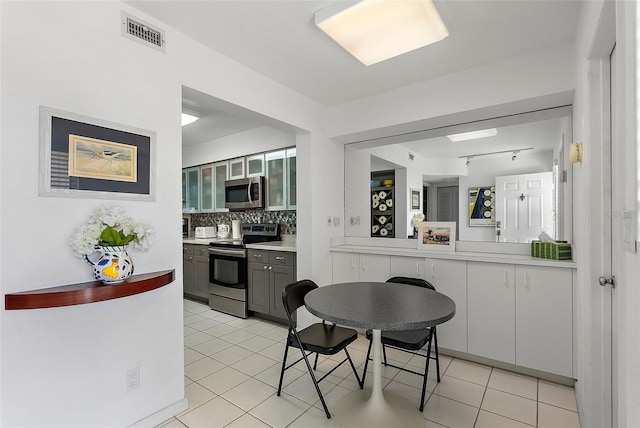 kitchen featuring visible vents, light countertops, appliances with stainless steel finishes, backsplash, and glass insert cabinets