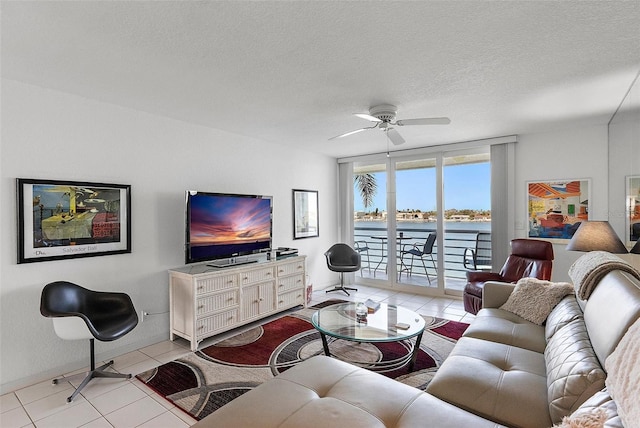 living room featuring light tile patterned floors, ceiling fan, a textured ceiling, and baseboards