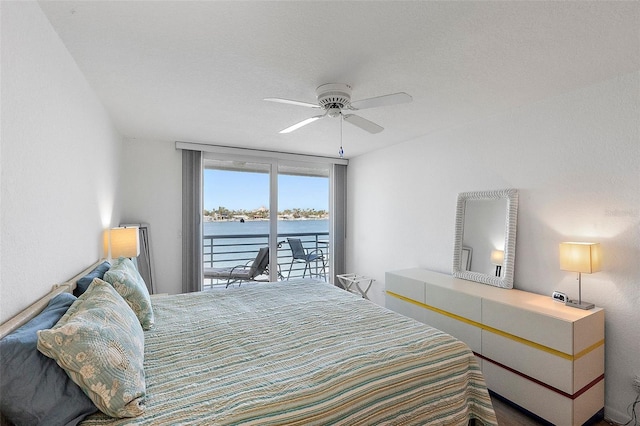 bedroom featuring ceiling fan, a water view, and access to exterior