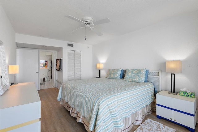 bedroom with a closet, wood finished floors, visible vents, and a ceiling fan