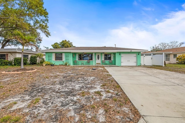 single story home featuring a garage, concrete driveway, a gate, a porch, and stucco siding