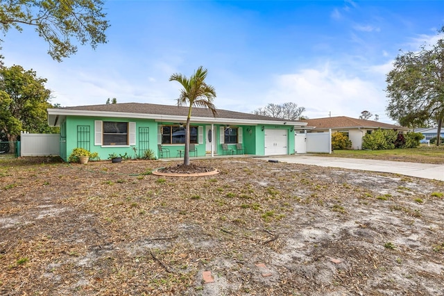 ranch-style home with a garage, concrete driveway, fence, and stucco siding