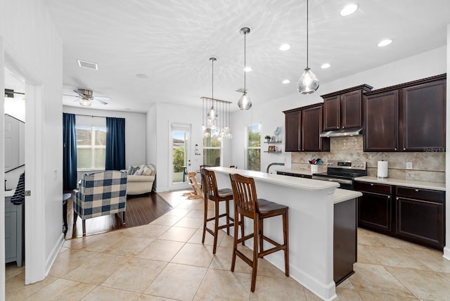 6157 Castleton Hollow Rd, Riverview, FL 33578 - kitchen featuring electric stove, light countertops, tasteful backsplash, dark brown cabinets, and a breakfast bar area