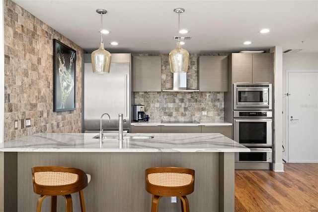 kitchen with a sink, light stone countertops, appliances with stainless steel finishes, and a breakfast bar area