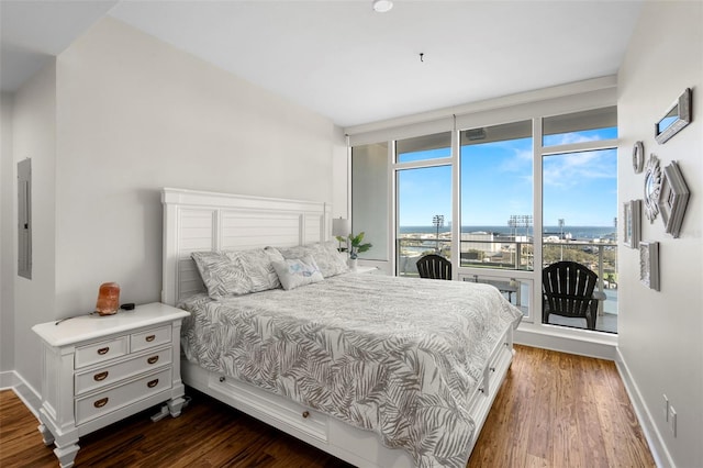 bedroom with baseboards, dark wood-style flooring, access to outside, a view of city, and floor to ceiling windows