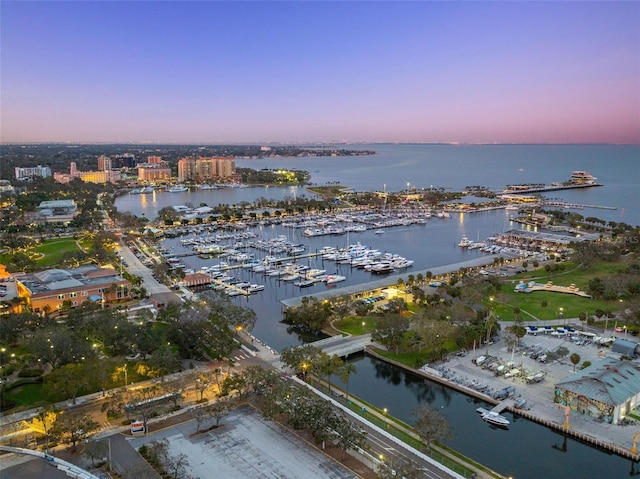 aerial view at dusk featuring a water view and a city view