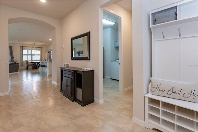 hall featuring arched walkways, light tile patterned floors, baseboards, and recessed lighting