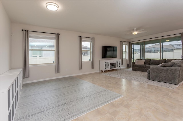 living area with light tile patterned floors, baseboards, and a ceiling fan