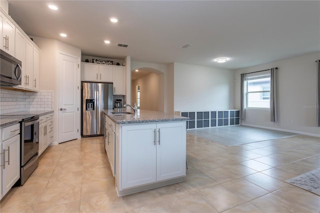 kitchen with appliances with stainless steel finishes, a center island with sink, and white cabinets