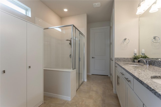 full bathroom featuring double vanity, a shower stall, a sink, and tile patterned floors