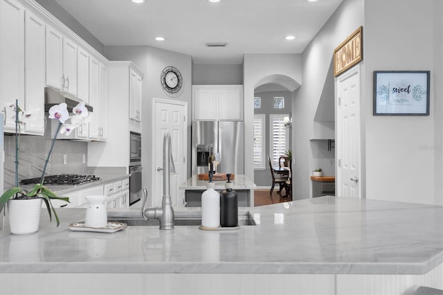 kitchen featuring stainless steel appliances, visible vents, a kitchen island, and white cabinetry