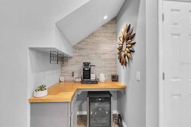 bar with beverage cooler, a dry bar, and vaulted ceiling