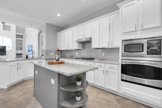 kitchen with a center island, stainless steel appliances, under cabinet range hood, white cabinetry, and open shelves