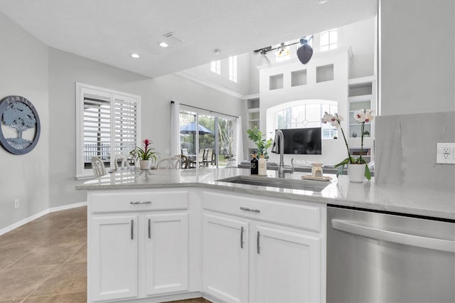 kitchen with a sink, light stone countertops, white cabinets, and stainless steel dishwasher