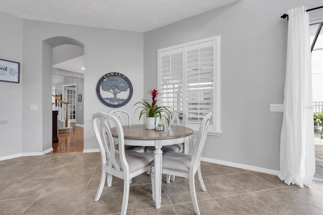 tiled dining room featuring a healthy amount of sunlight, stairway, and baseboards