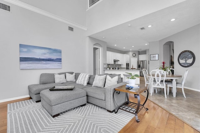 living area with light wood finished floors, visible vents, arched walkways, and baseboards