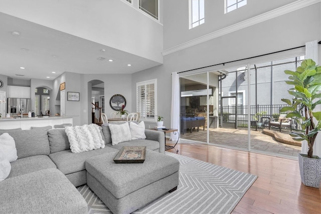 living area with arched walkways, wood finished floors, and recessed lighting