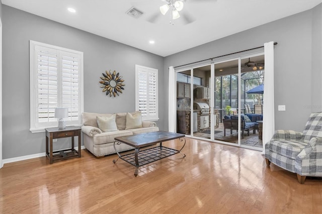 living area featuring visible vents, ceiling fan, baseboards, and wood finished floors