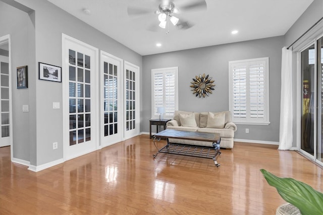 living area with a healthy amount of sunlight, baseboards, visible vents, and wood finished floors